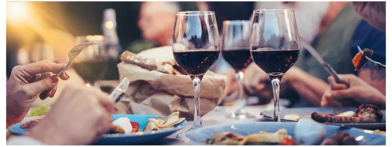 Table laden with plates of barbecue food and wine glasses