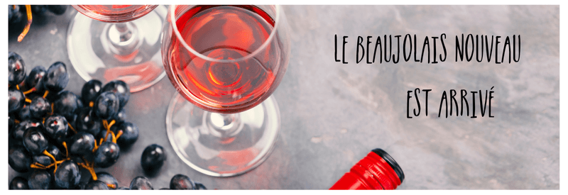 Glass of light coloured red Beaujolais wine with black grapes and caption "Le Beaujolais nouveau est arrivé!"