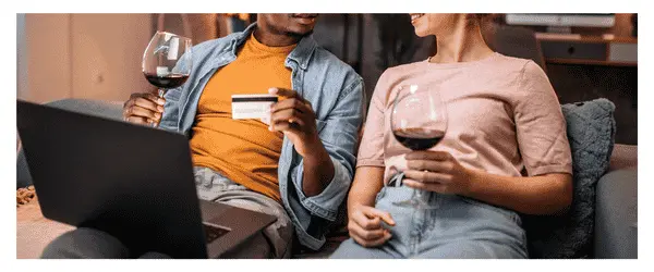 Couple on a sofa with a laptop and a glass of wine buying wine online