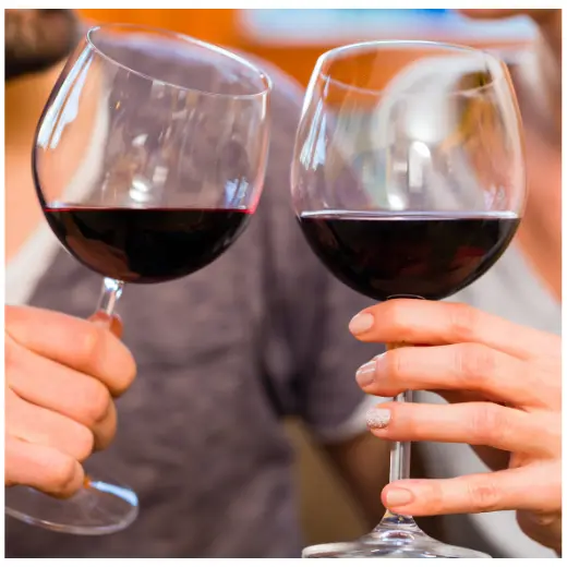 Close up of two glasses of Pinot Noir being held by a man and a woman