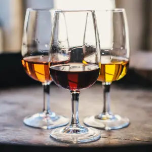 Three glasses of different ports on a dark wooden table