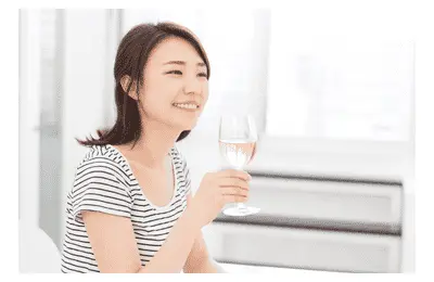 Young woman smiling and holding a glass of white wine