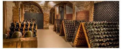 Champagne aging in bottles in riddling tables and in stacks in a traditional stone and wood-framed wine cellar