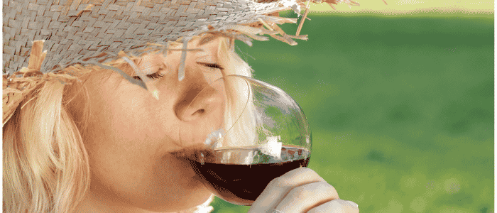 Lady with sun hat sipping red wine in hot weather