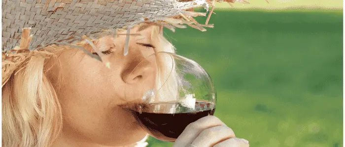 Lady with sun hat sipping red wine in hot weather