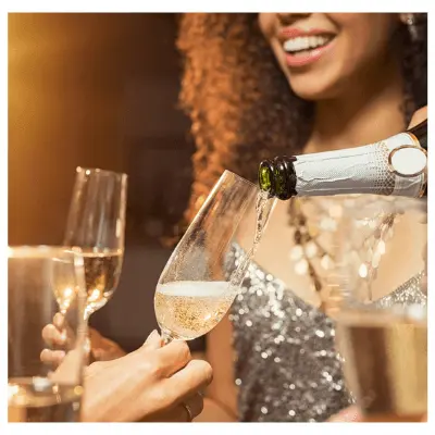 Woman holding glass of sparkling wine watching someone pouring