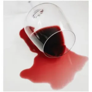 Glass of red wine on its side, wine spilling onto white table
