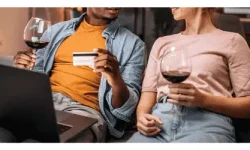 Couple on a sofa with a laptop and a glass of wine buying wine online