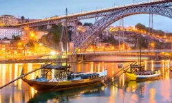 An evening view of Porto harbour with metal bridge over the river Douro and some traditional boats