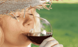 Lady with sun hat sipping red wine in hot weather