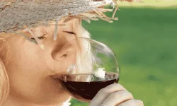 Lady with sun hat sipping red wine in hot weather